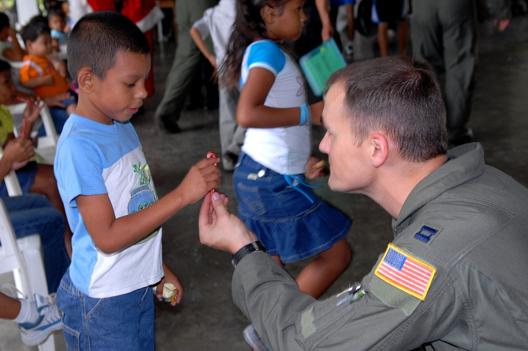 Capt. Patrick Dube, an aircraft commander with the 9th Special Operations Squadron, hands a Honduran orphan a candycane at Aldea Infantil S.O.S Orphanage in La Ceiba, Honduras during Operation Christmas Wish Dec. 13. Captain Dube was part of a 16-person team that helped deliver more than 875 Christmas packages to five different Honduran orphanages. (U.S. Air Force photo/Senior Airman Ali Flisek)